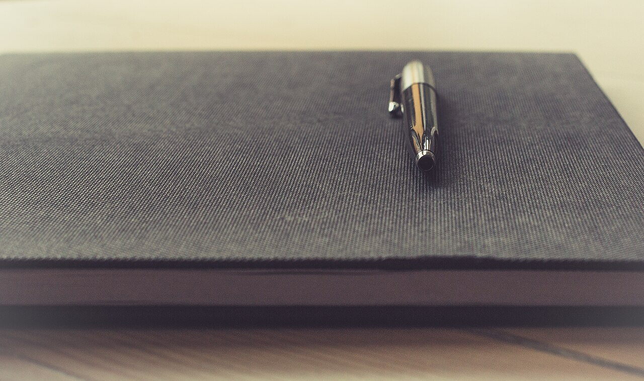 Pen resting on a closed textured notebook