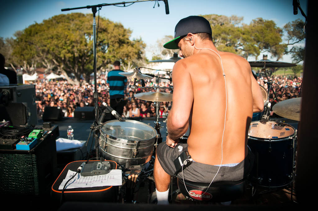 Drummer wearing in-ear monitors on an outdoor stage